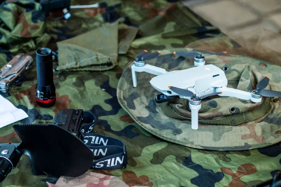 A small quadcopter drone and field kit laid out on camouflage cloth