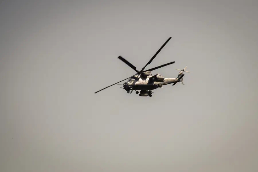 A military helicopter in flight against a grey sky